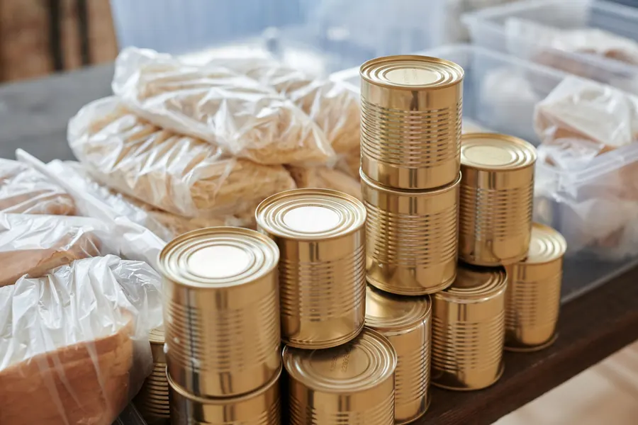 Stacked canned goods and bagged bread on a pantry table