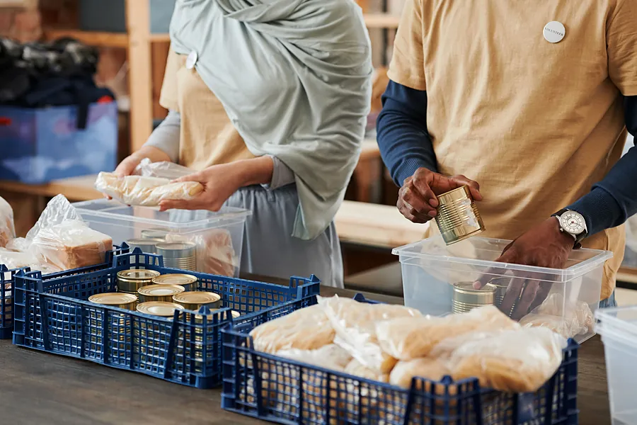 Volunteers sorting bagged bread and canned goods into blue crates and clear bins