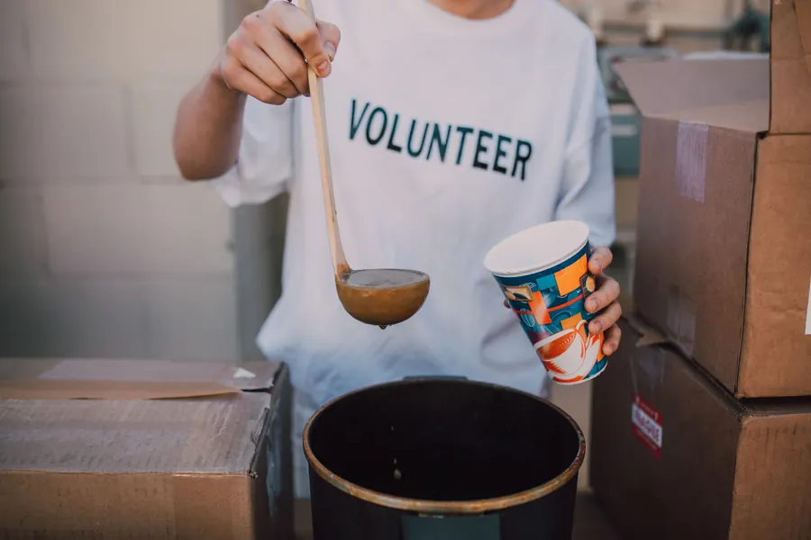 A volunteer ladling soup into a cup at a community meal